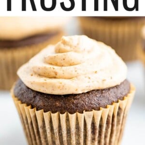 A chocolate cupcake in a brown wrapper topped with healthy greek yogurt frosting. The cupcake is resting on a gold wire rack.