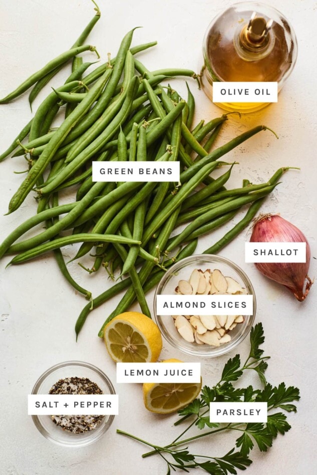 Ingredients measured out to make green beans almondine: olive oil, green beans, shallot, almond slices, lemon juice, salt, pepper and parsley.