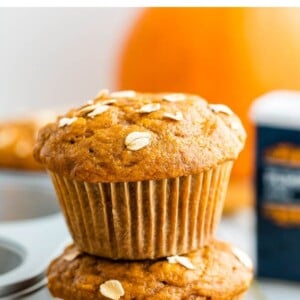 Stack of two healthy pumpkin muffins topped with oats. Muffins are on a gold wire cooling rack.