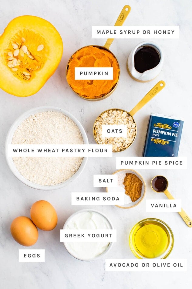 Ingredients measured out to make pumpkin muffins: maple syrup, pumpkin, oats, whole wheat pastry flour, pumpkin pie spice, salt, baking soda, vanilla, greek yogurt, eggs and olive oil.