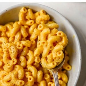 Bowl of vegan mac and cheese with a spoon. Text reads "Vegan Mac and Cheese, Plant-based and super creamy"