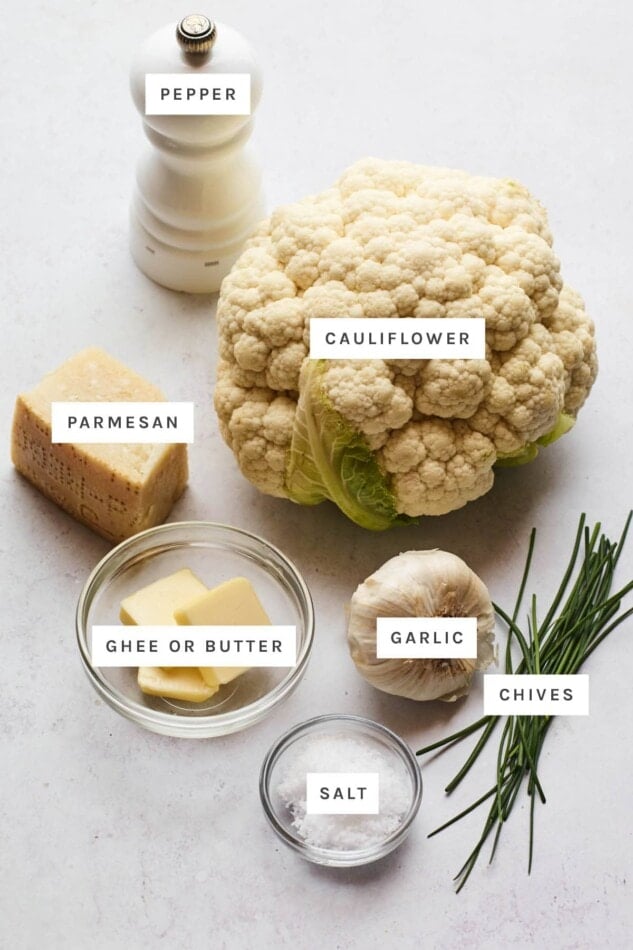Ingredients measured out to make mashed cauliflower: cauliflower, pepper, parmesan, garlic, butter, chives and salt.