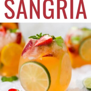 A glass of white wine sangria with a lime slice perfectly showing through the glass.