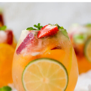 A glass of white wine sangria with a lime slice perfectly showing through the glass.