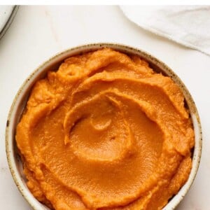 Bowl of sweet potato puree with a spoon next to it.