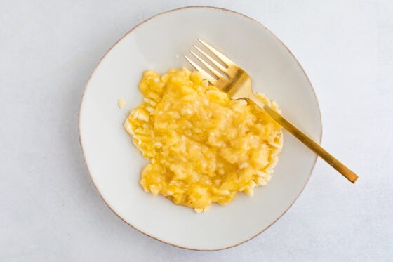 An overhead photo of a plate with mashed banana. A fork is resting on the plate.
