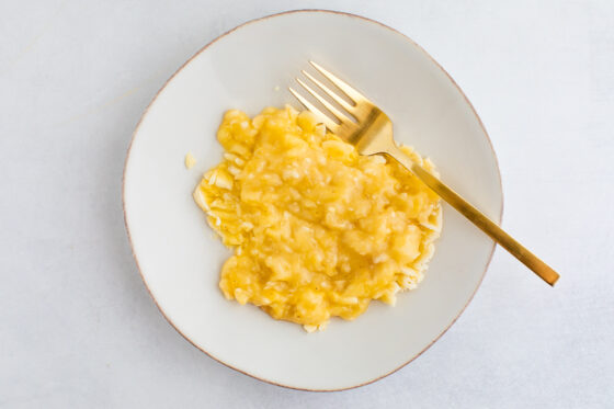 An overhead photo of a plate with mashed banana. A fork is resting on the plate.