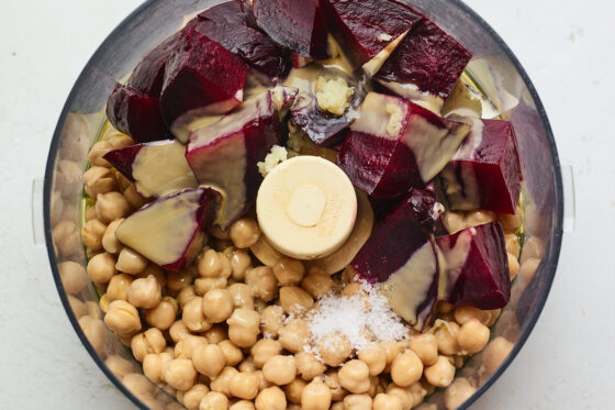 A food processor with ingredients for beet hummus.