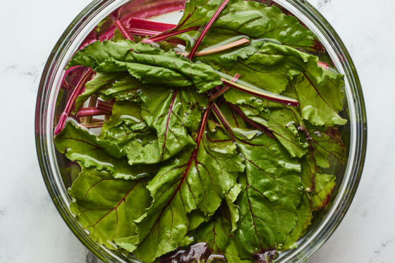 A bowl of beet greens in a bowl with water.