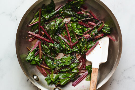 Freshly sautéed beet greens in a sauté pan with a spatula.