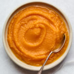 A bowl of butternut squash puree with a spoon.