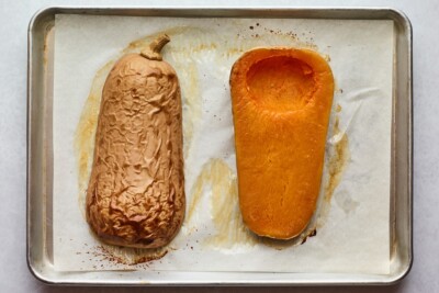 Freshly roasted butternut squash on a piece of parchment paper on a sheet pan.