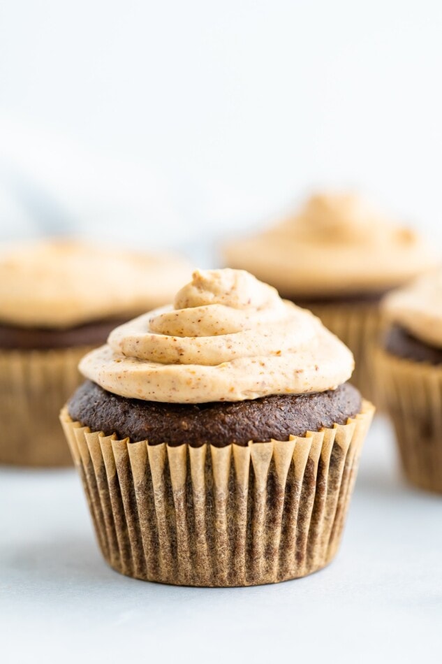 A chocolate cupcake in a brown wrapper topped with healthy greek yogurt frosting.