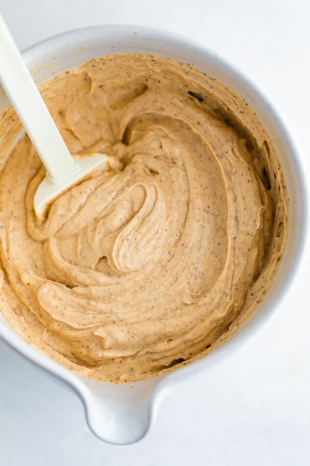 An overhead photo of a mixing bowl with healthy greek yogurt frosting. There is a spatula resting in the bowl.