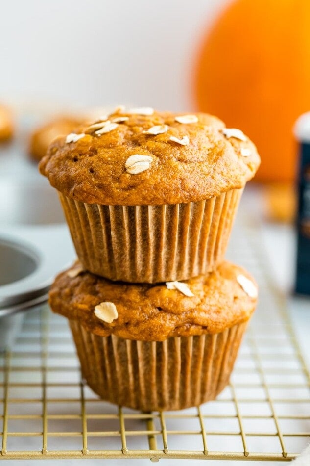 Two pumpkin muffins stacked on top of a wire rack.