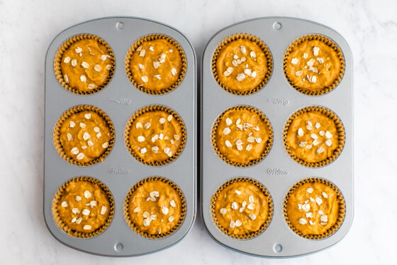 Pumpkin muffin battered divided between 2 6-muffin tins lined with brown cupcake liners.