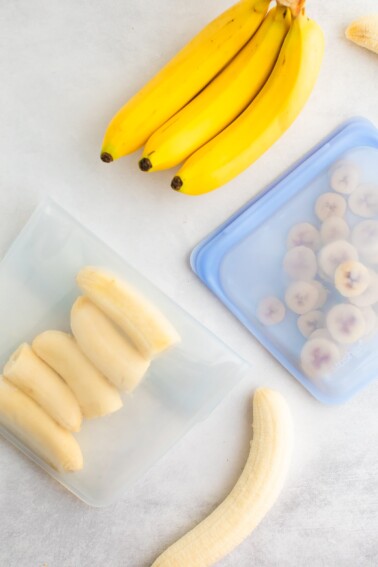 An overhead photo of two stasher bags. In one stasher bag is banana halves and the other has banana slices.