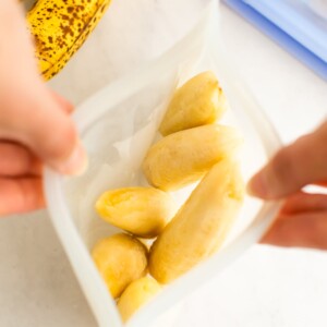 An overhead photo looking into a stasher bag that is being held open by two hands. Inside the bag you can see banana halves.