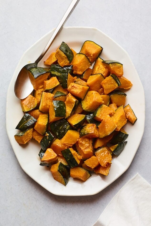 An overhead photo of a serving dish full of Kabocha tots. A spoon rests inside the dish with the tots.