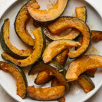 An overhead photo of a plate of cinnamon roasted Kabocha squash slices. A fork rests next to the plate.