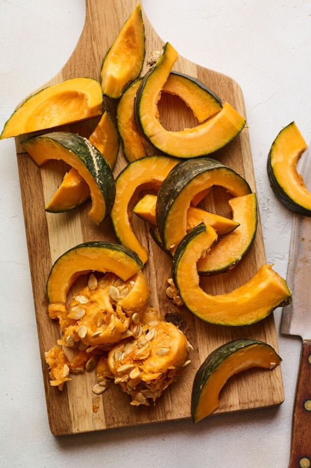 A cutting board with a Kabocha squash sliced and deseeded.