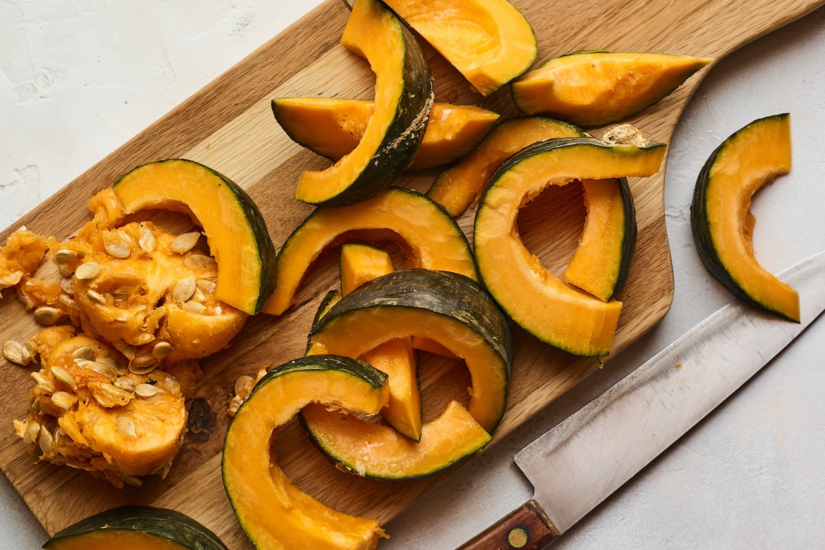 A cutting board with a Kabocha squash sliced and deseeded.