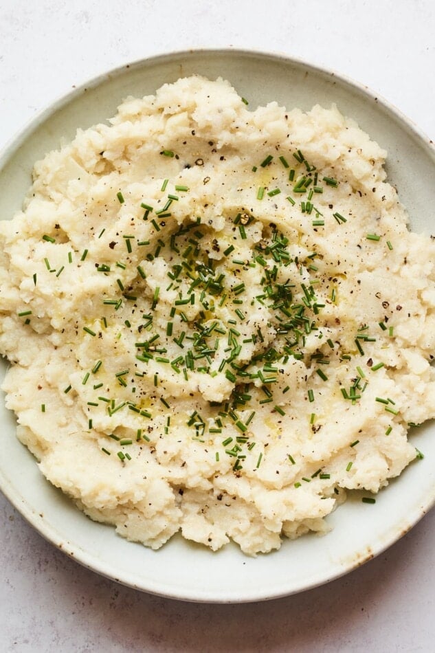 A bowl of mashed cauliflower topped with chives.