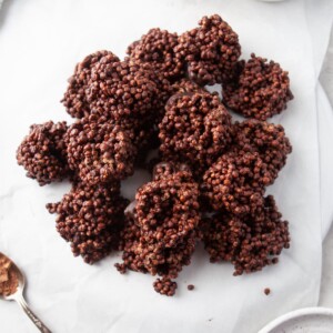 An overhead photo looking at chocolate quinoa crunch bites piled onto pieces of overlapping parchment paper.