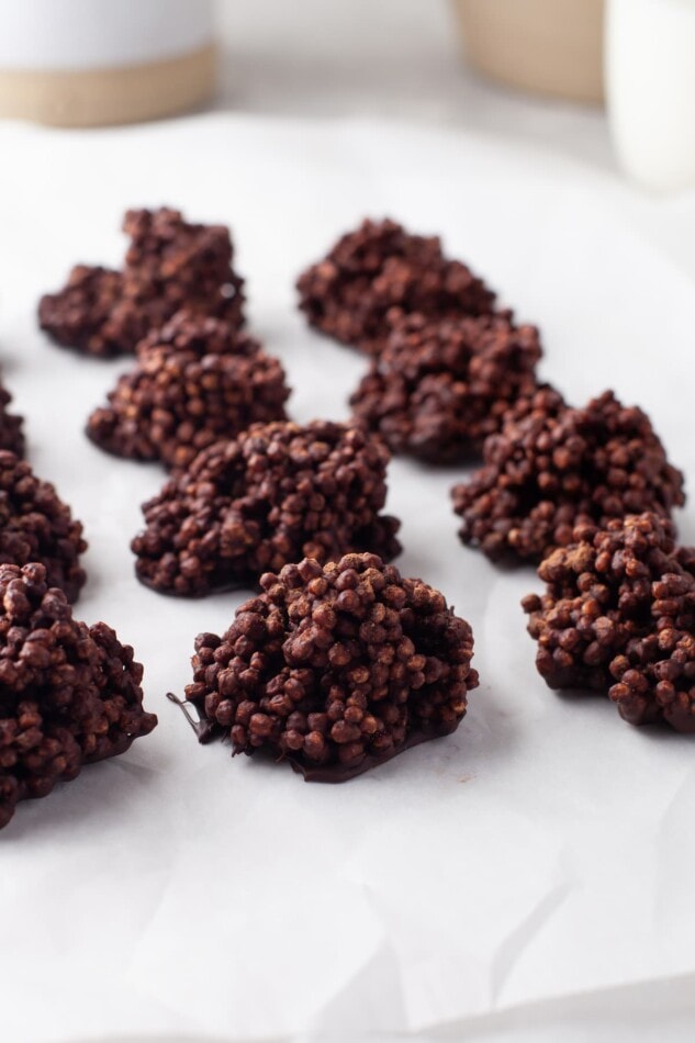 Quinoa crunch bites in 2 rows of 4 on parchment paper. There is a 3rd row being cut out of the frame.