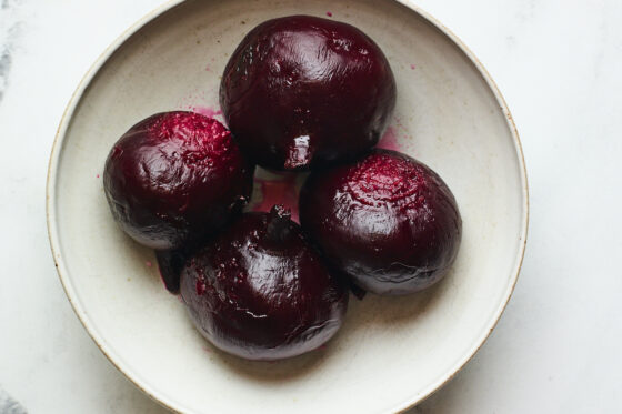 4 freshly roasted beets in a shallow bowl.