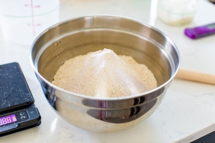 A metal mixing bowl with measured out flour.