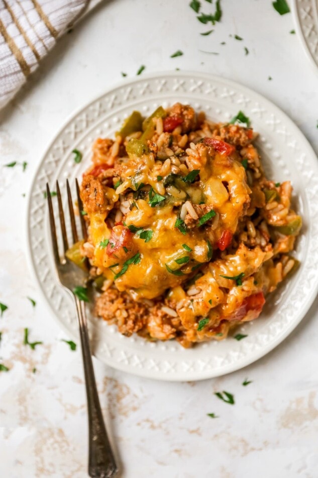 An overhead photo of stuffed pepper casserole served on a round, white plate. A fork is resting on the plate.