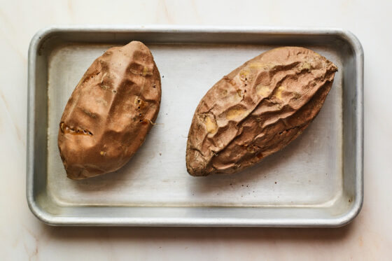 Two freshly baked sweet potatoes on a pan.