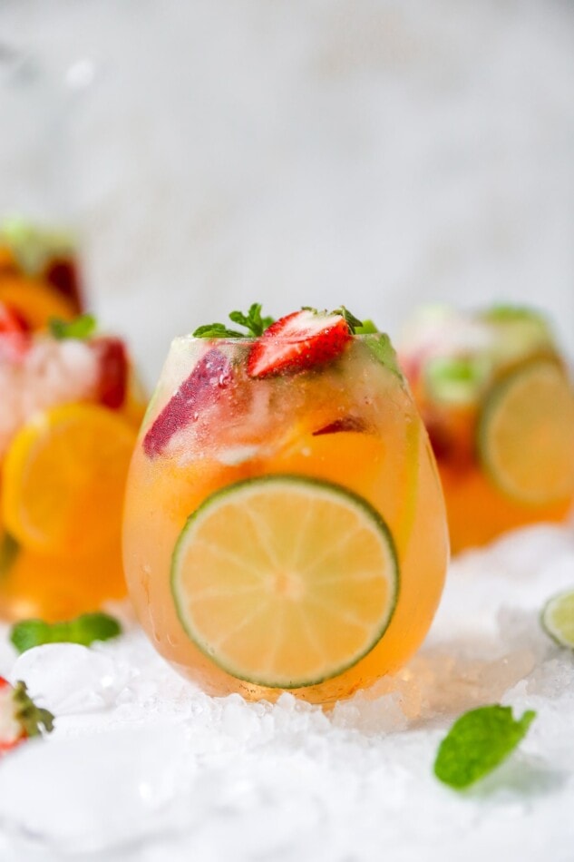 A glass of white wine sangria with a lime slice perfectly showing through the glass.