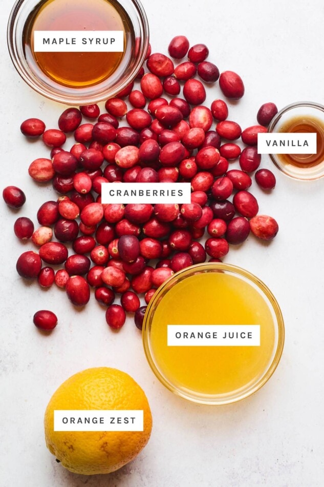Ingredients measured out to make cranberry sauce: maple syrup, vanilla, cranberries, orange juice and an orange for orange zest.