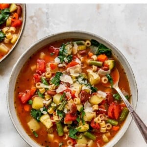 Bowl of minestrone soup with a spoon and topped with parmesan.