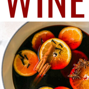 A large pot containing mulled wine with orange slices, cinnamon sticks, cloves and star anise floating in the wine.