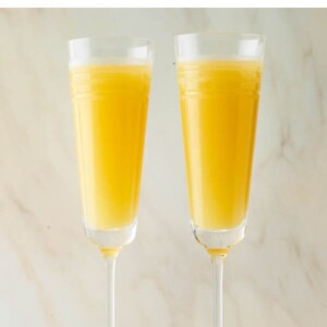 Two champagne flutes with mimosas.
