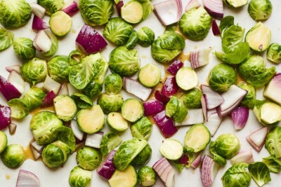 A sheet pan with Brussel sprouts and red onion spread around.