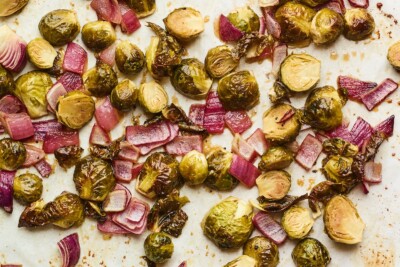 A sheet pan with freshly roasted apple cider vinegar roasted Brussels sprouts with red onion.