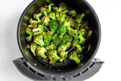 An air fryer basket containing perfectly air fried broccoli.