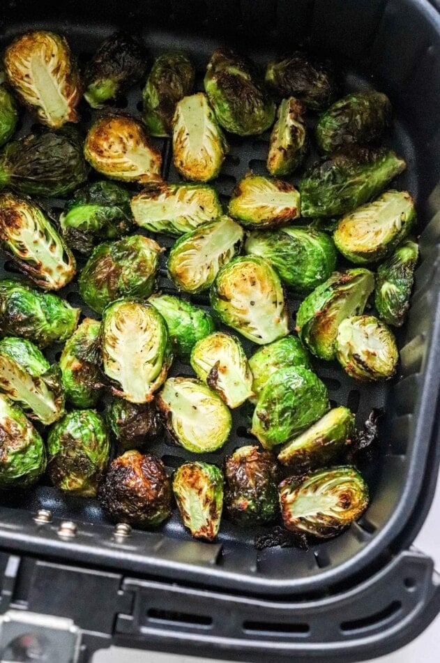 A close up of air fried brussels sprouts in an air fryer basket.