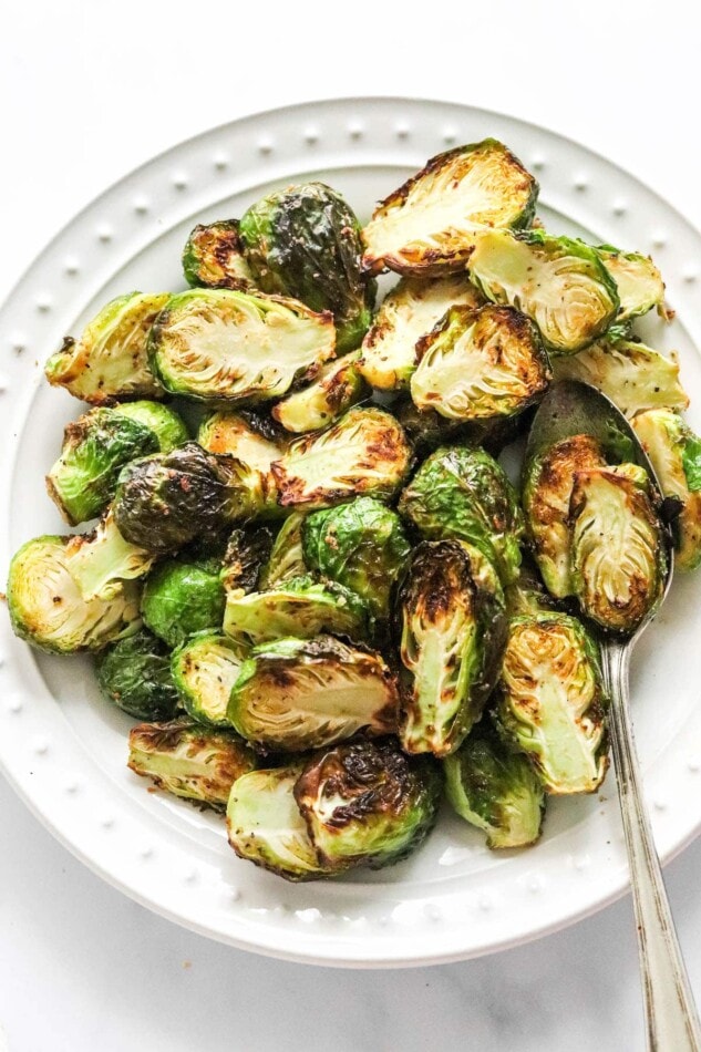 Air fryer brussels sprouts on a plate with a serving spoon.