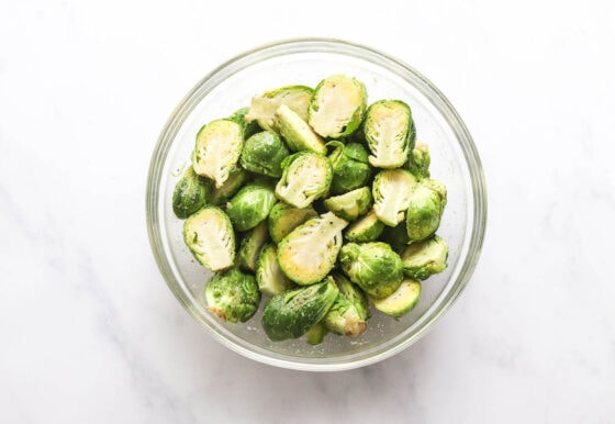 Chopped and seasoned brussels sprouts in a glass mixing bowl.