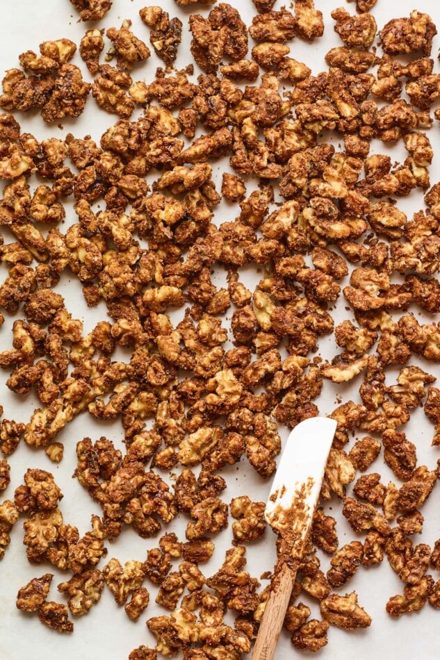 Candied walnuts spread across a piece of parchment paper to cool.