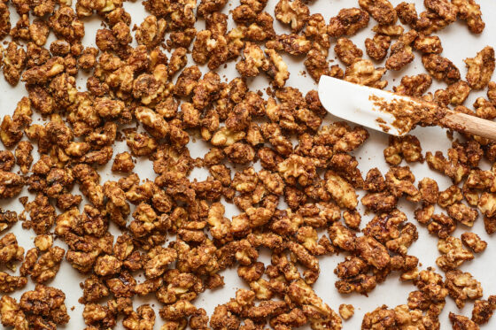 Candied walnuts spread across a piece of parchment paper to cool.