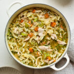Overhead view of a dutch oven containing chicken noodle soup.
