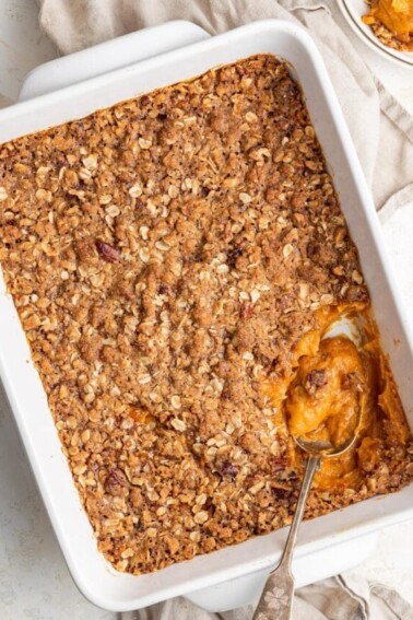 Healthy sweet potato casserole in a baking dish with a spoon.