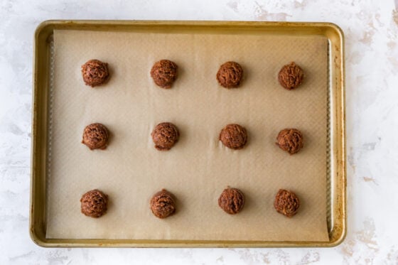 A sheet pan with almond butter espresso cookie dough evenly placed in three rows and four columns.