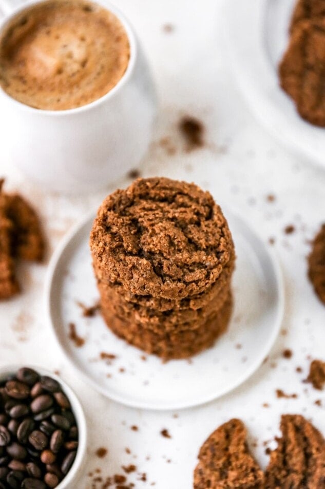 A stack of almond butter espresso cookies on a plate. A mug of hot cocoa is next to the plate.